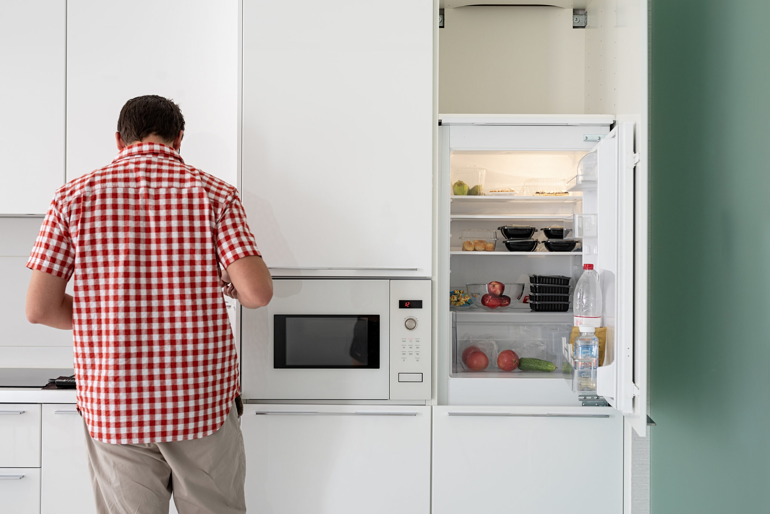 Young Man Makind Tea Standing Next To The Open Fridge.